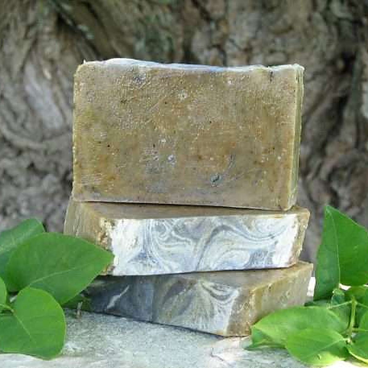 Savons artisanaux aux 4 herbes sacrées empilés sur une pierre avec des feuilles