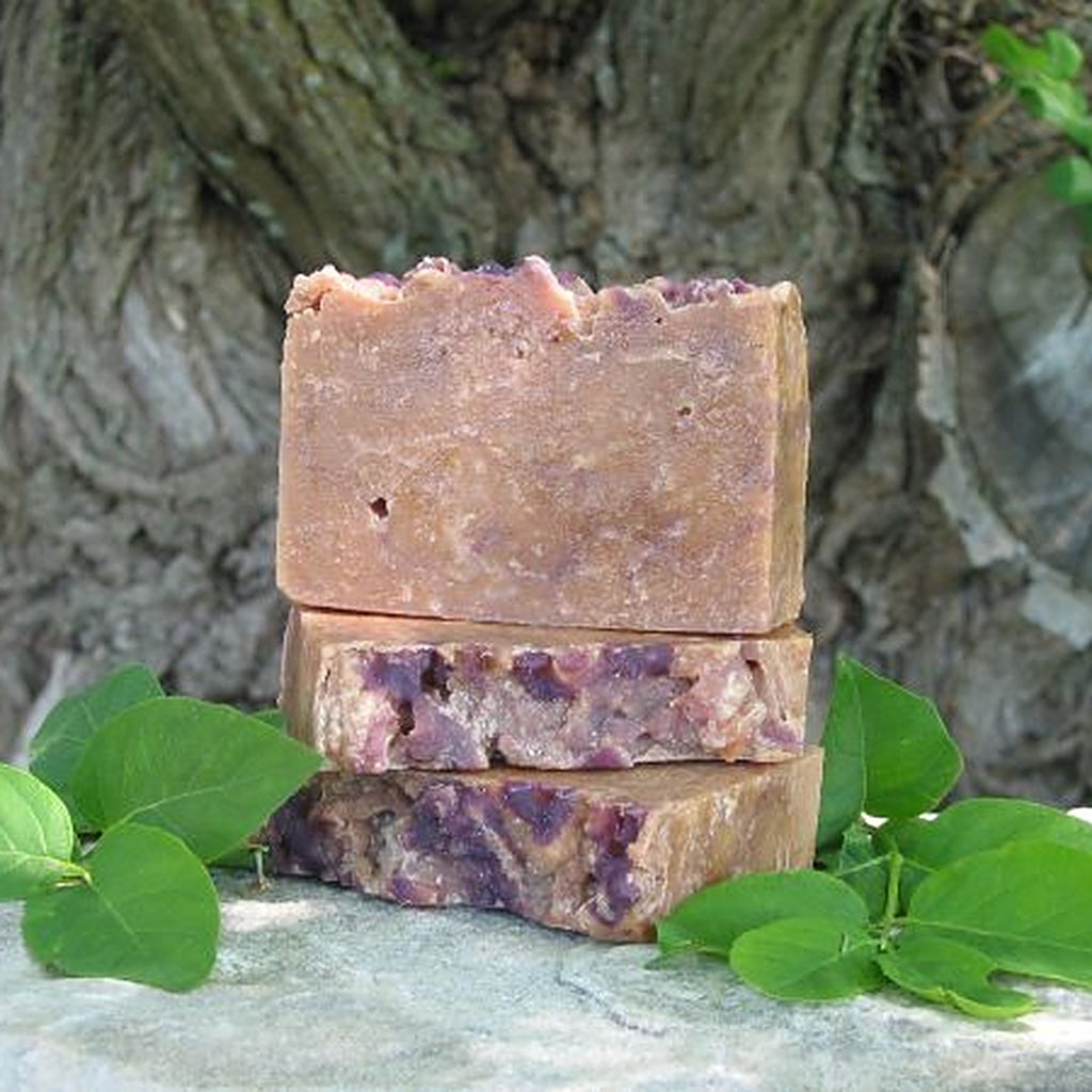 Savons artisanaux à la fleur de sureau empilés sur une pierre avec des feuilles